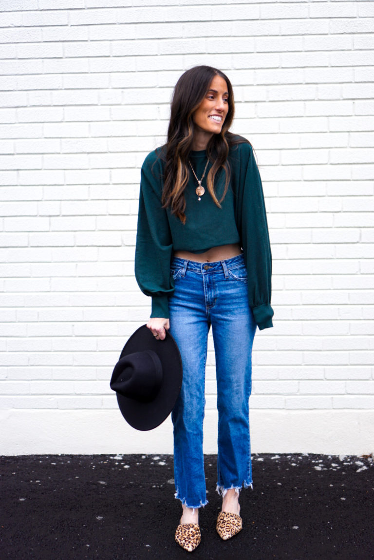 Woman wearing cropped sweater with high waisted mom jeans, wide brim hat, and leopard mules