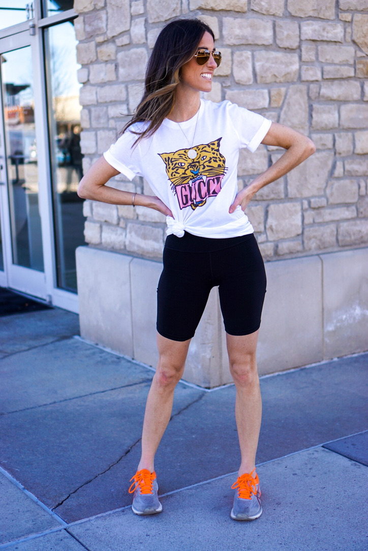 Women wearing a Gucci T-shirt that is side knotted and biker shorts